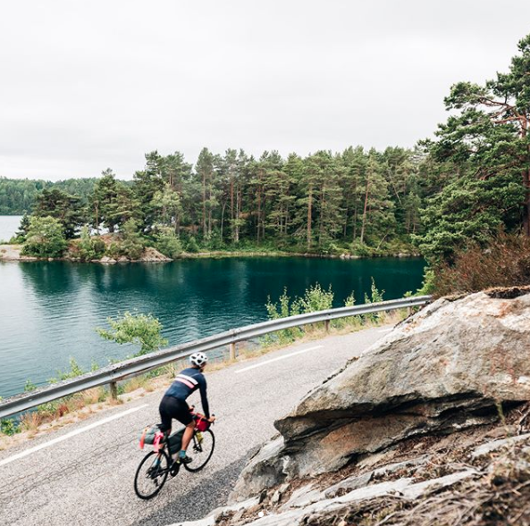 Gustav Thuesen cycling alongside a lake